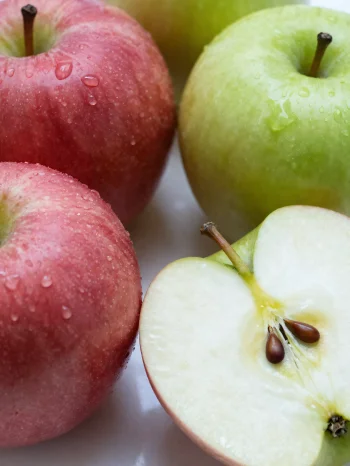 Ferske røde og grønne epler på skjærefjøl, i skiver og hele, med eplejuice