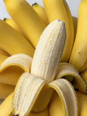 Ferske bananer hele og i skiver, i skål og på rustikt bord