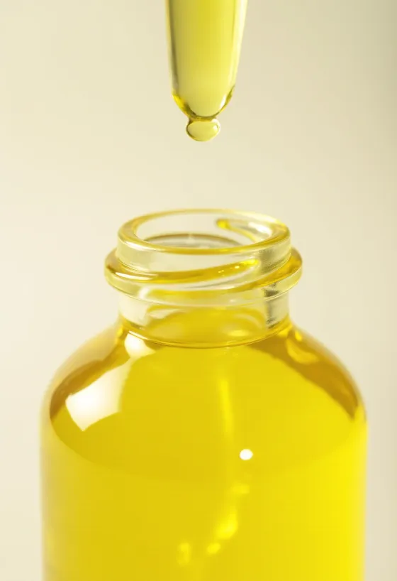 Sitronolje i liten flaske, ved siden av ferske sitronskiver og revet skall