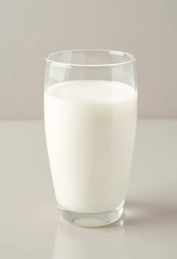 Et glass og en flaske fersk melk på lys kjøkkenbenk, uten dyremotiver