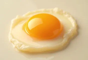 Separert rå eggeplomme i glassbolle på treoverflate