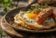 Alheira-pølse servert med speilegg, drysset med persille, på en rustikk tallerken