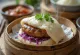 Bao med stekt pølse servert med kålblanding og frisk koriander