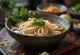 Pho med sesamolje servert i bolle, sesamolje-risnudelsuppe, fersk koriander og limeskiver