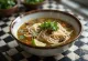Pho sursøt variant servert i en bolle med sursøt risnudelsuppe, frisk koriander og limeskiver