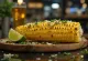 Elote med smør, pyntet med parmesan og koriander